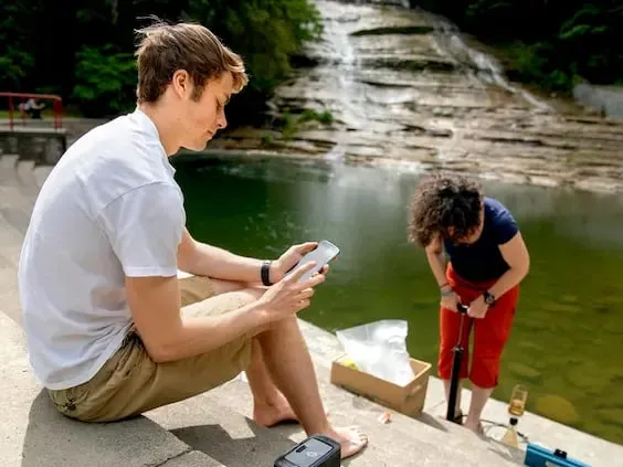 Researchers collecting water quality samples in the field near a waterfall
